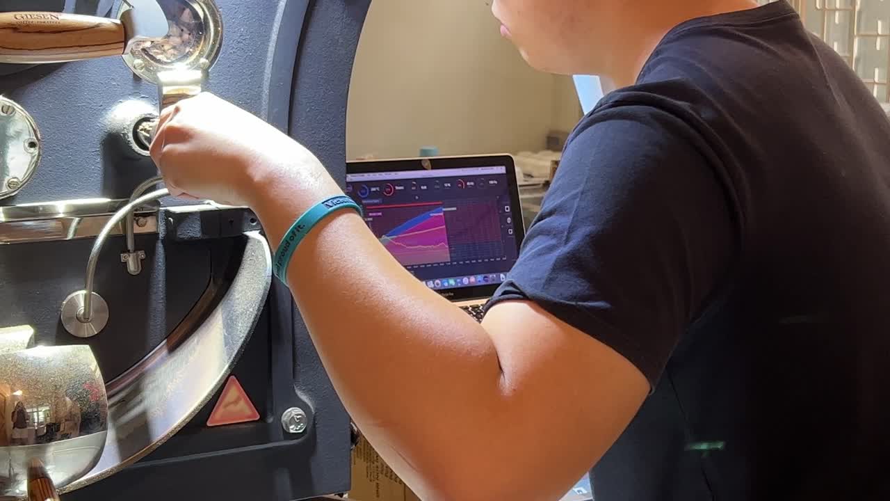 노트북 그래프 디스플레이 및 온도 열 제어를 모니터링하는 젊은 커피 전문직은 원두가 완벽하게 로스팅되도록 보장하고 로스터 창고 공장 공급