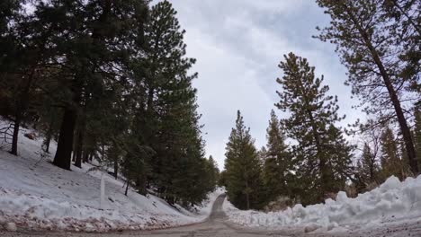 carretera helada de invierno en las montañas tehachapi, california con acumulación de nieve y una sobrecarga de cloudscape - lapso de tiempo