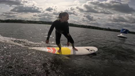 Una-Chica-Surfea-Olas-En-Un-Longboard-Detrás-De-Un-Barco-Con-Muchas-Nubes-En-El-Cielo-Con-Gopro-60fps