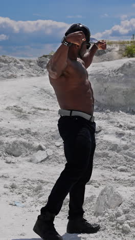 full length view of the muscular shirtless handsome man posing for camera. athletic young bodybuilder with naked torso showing his biceps. vertical video