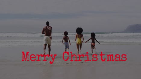 animación de saludos de navidad texto sobre familia afroamericana en la playa.