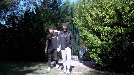 slow motion shot of 2 young musicians walking through a gate