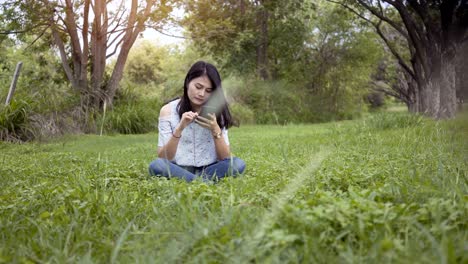 asian women play mobile phones at the park happily.