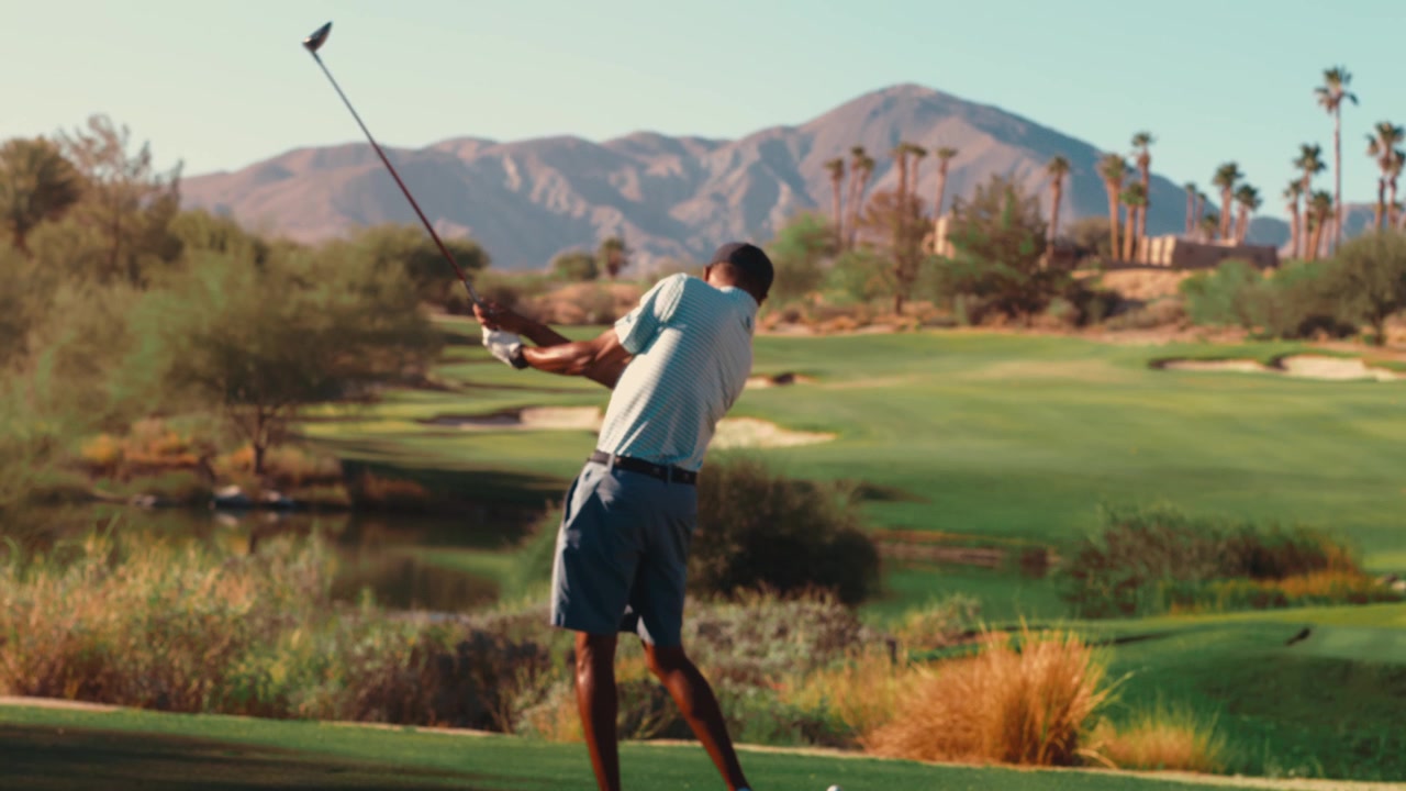 African American golfer taking practice swing on beautiful desert mountain golf course in slow motion preparing for tee shot