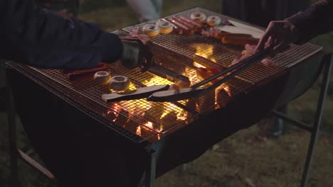 people standing in front of the bbq and grilling mushrooms, sausage, chicken, eggplant in front of the house in a garden