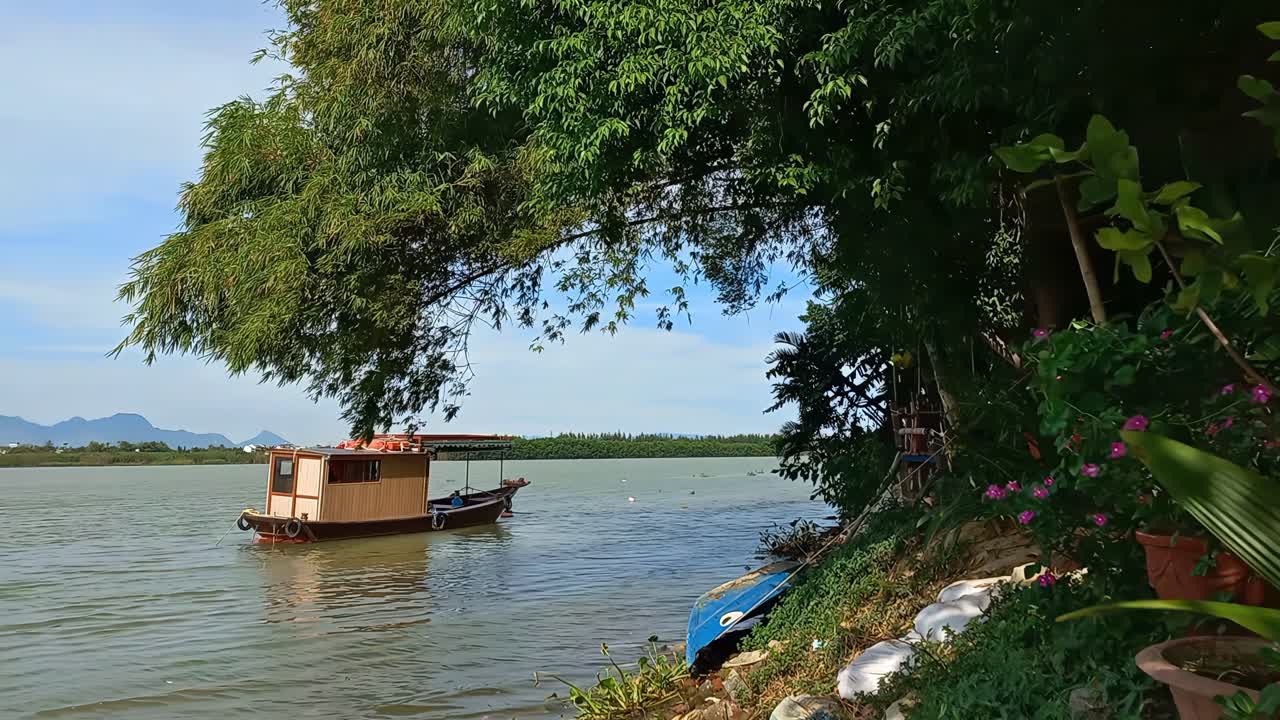 Traditional Wooden Boat on a Serene River with Lush Greenery and Mountains