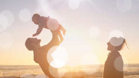 Animation-Von-Bokeh-über-Einer-Glücklichen-Kaukasischen-Familie,-Die-Bei-Sonnenuntergang-Am-Strand-Spielt