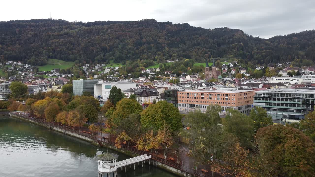 Beautiful city of Bregenz with its alpine buildings on the edge of a lake Constance with its calm rippling water and its gazebo in the middle of the Austrian alps, aerial view