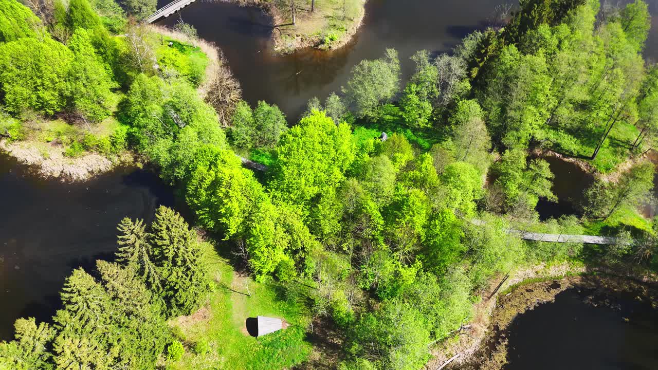 A Peaceful Island Connected by Winding Bridges Sits Amid the Karst Lakes of Kirkilai, Biržai Regional Park, Lithuania - Aerial Drone Shot