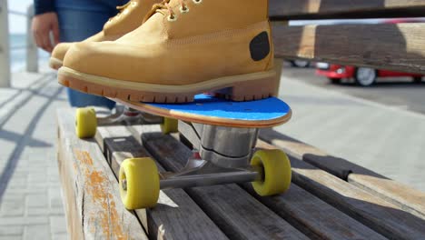 close-up of man sitting on skateboard near beach 4k