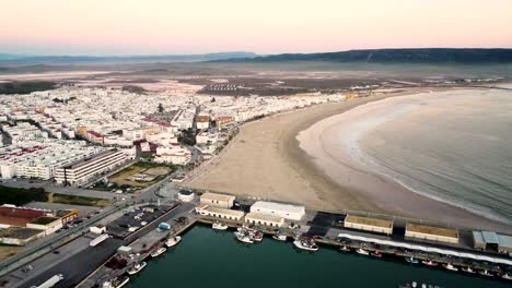 Aerial-flyover-a-busy-port-and-the-local-town-in-Barbate,-Spain