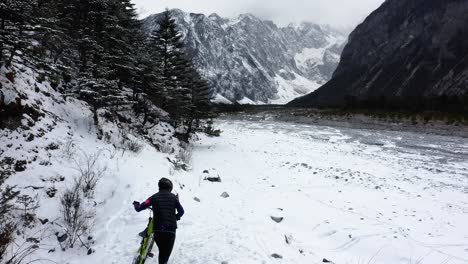 Extreme-mountain-biker-cycling-up-steep-snowy-mountainside,-aerial-view