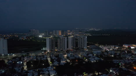 Hacia-Adelante,-Elevándose,-Vuela-Sobre-La-Ciudad-Nocturna.-Modernos-Edificios-Altos-De-Apartamentos-En-Complejo-Residencial-De-Lujo.-Cancún-México