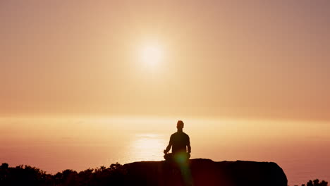 hombre meditando al atardecer con vistas al océano