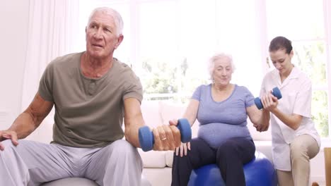 Smiling-nurse-helping-senior-couple-doing-exercises