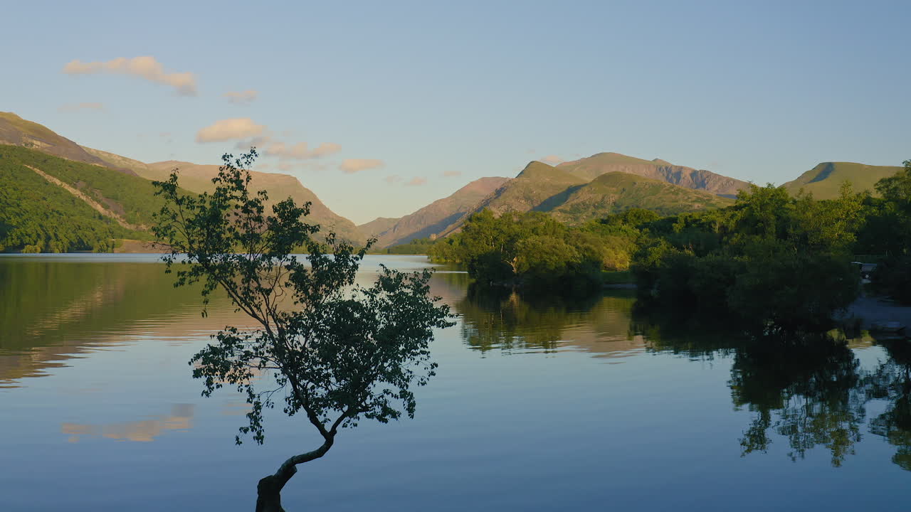 Tranquil Scenery At The Llyn Padam Lake, with a perfect reflection of a tree in Snowdania Wales UK - aerial shot