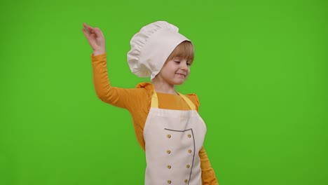 child girl kid dressed as cook chef raising hands, showing tasty gesture, smiling, looking at camera