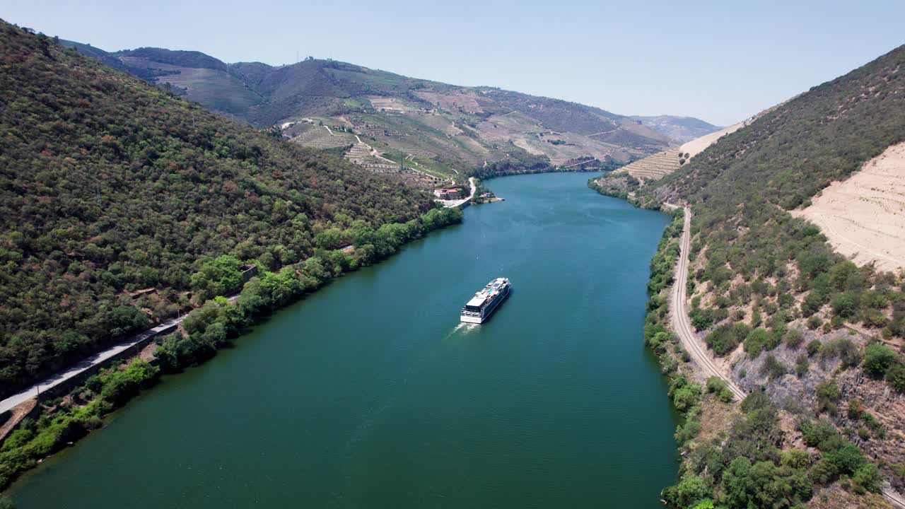 Nave da crociera che naviga sul fiume Douro in una valle collinare, Portogallo, drone