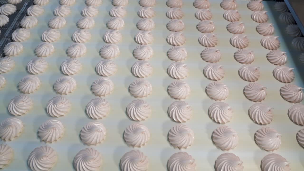 Sweet tender marshmallow moves on a conveyor belt. Automatic sweets production line at a candy factory