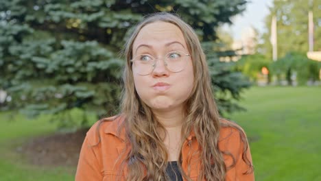 Woman-Holds-Breath-in-City-Park-Ending-with-Smiling-and-Looking-Around-Facing-Camera-with-Close-Up-Headshot