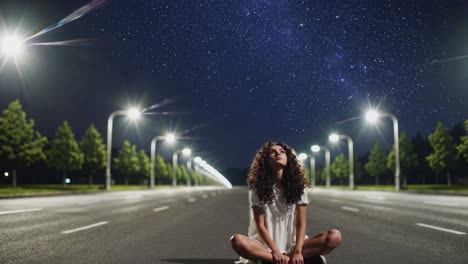 woman sitting on road at night under starry sky