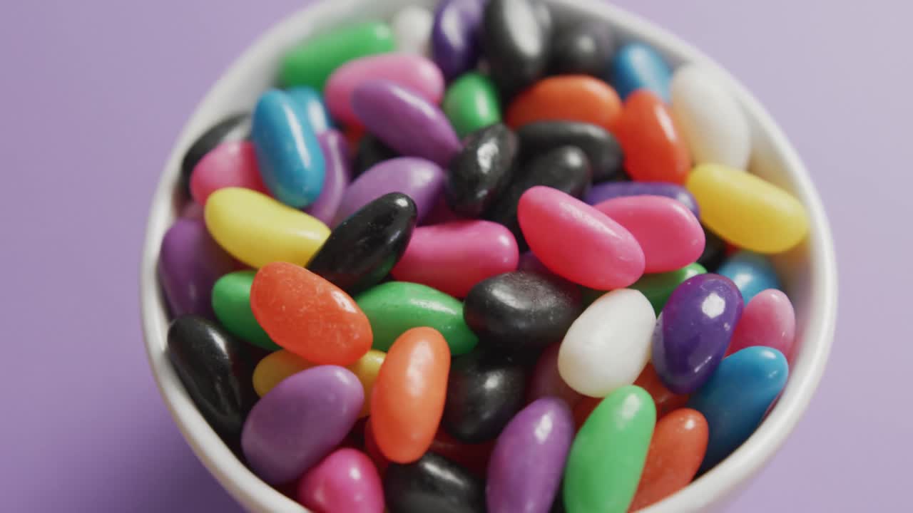 video de primer plano de dulces multicolores en un cuenco sobre un fondo púrpura