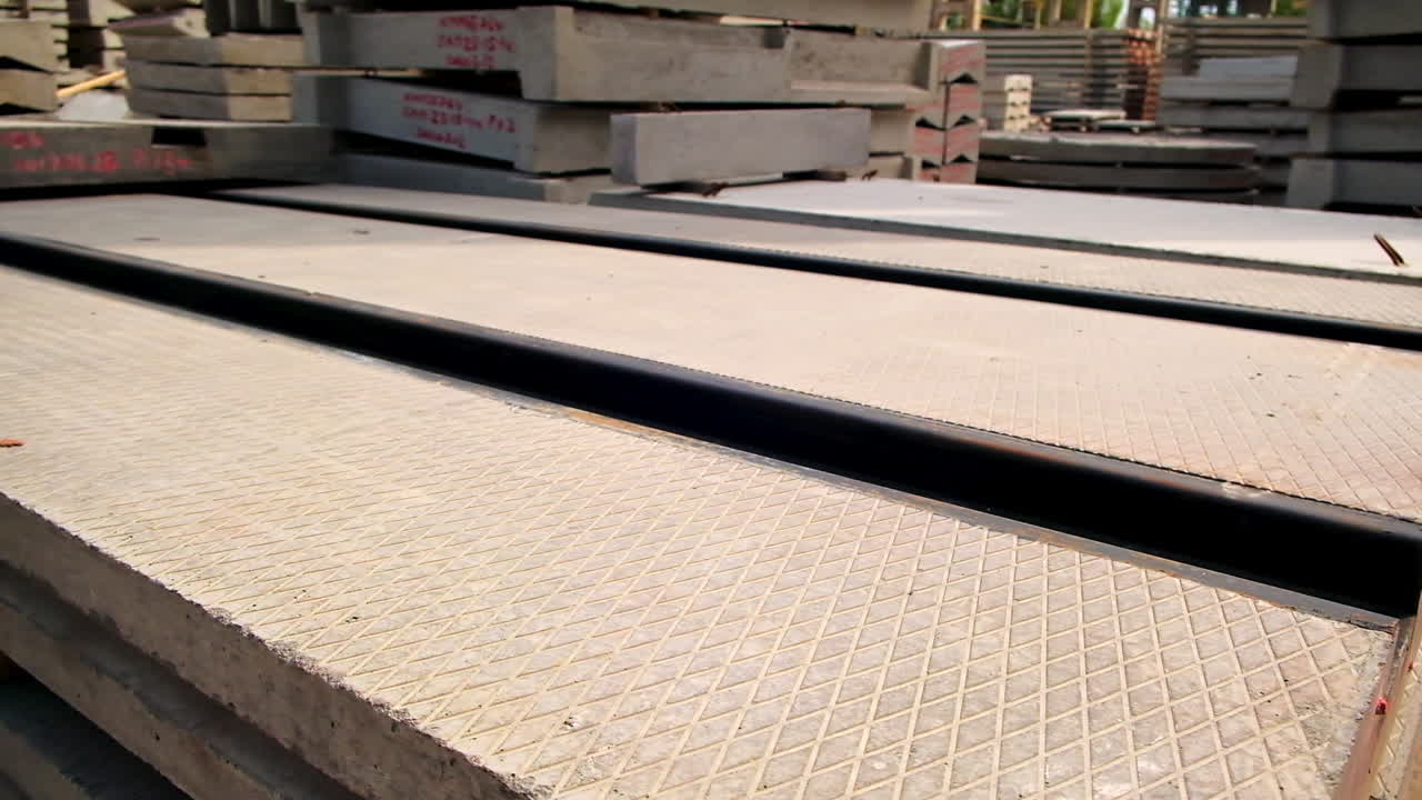 Large reinforced concrete plate with metal rails. Different ferroconcrete materials stored outside at construction site.