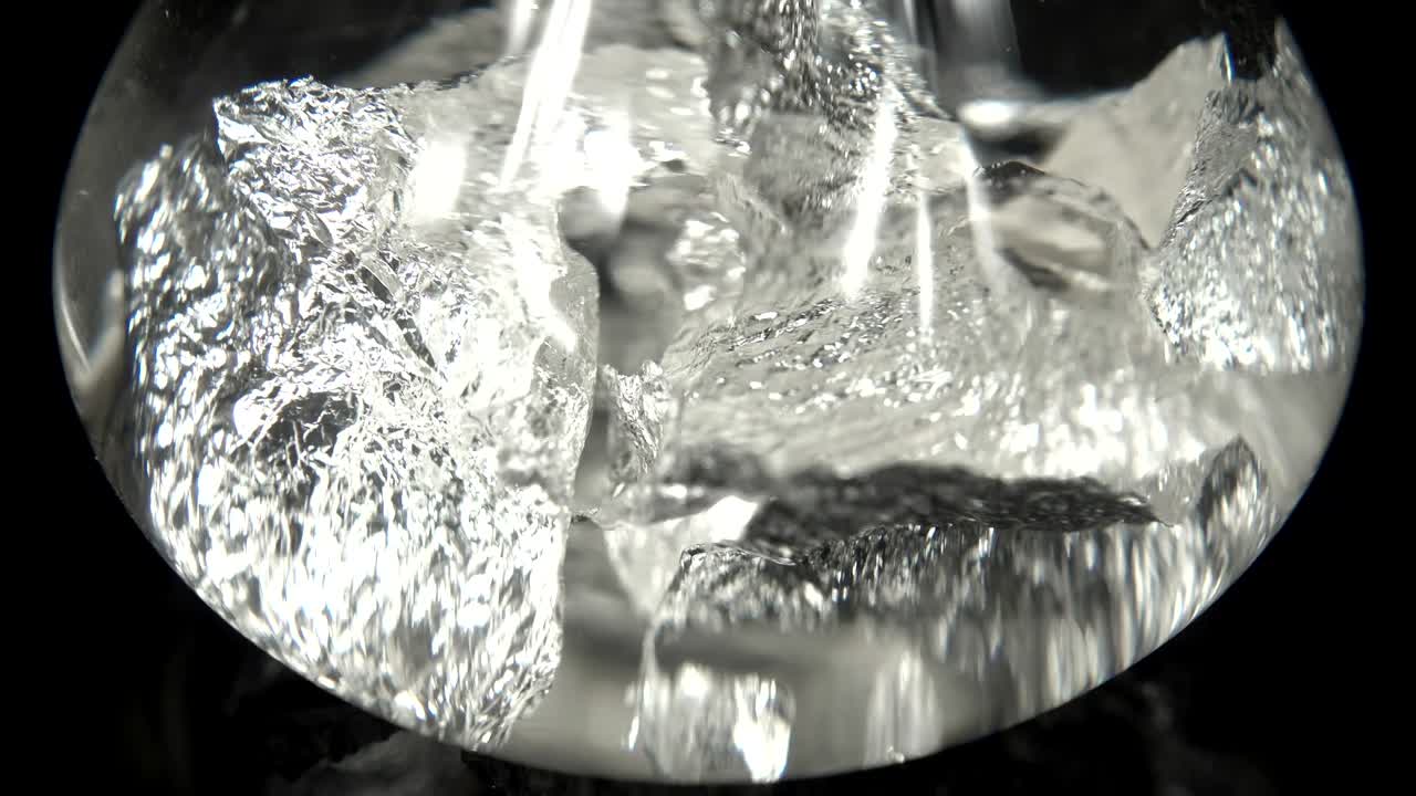 검은색 배경 앞에 물 속에서 원활하게 회전하는 은