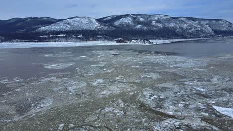 Aerial-drone-footage-of-an-icy-river-and-snow-covered-mountains-during-winter-in-America-in-the-Appalachian-mountain-range,-after-fresh-snowfall