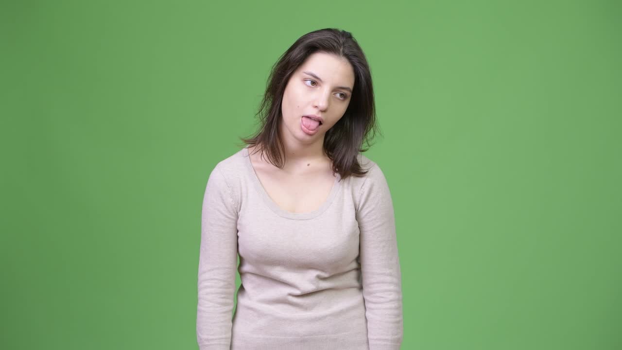 Young beautiful woman looking bored against green background