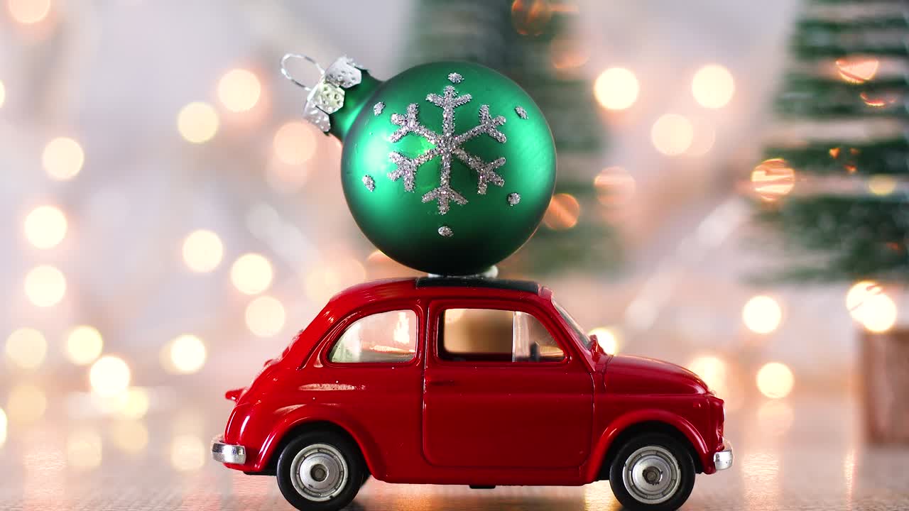 Little red car with green Christmas ornament on the roof and blinking lights