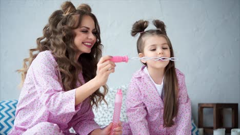 mother and daughter playing with bubbles in pajamas