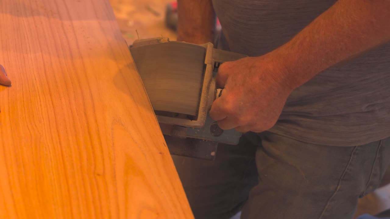 toma de seguimiento de un trabajador masculino lijando una mesa de madera en una lijadora eléctrica, de cerca
