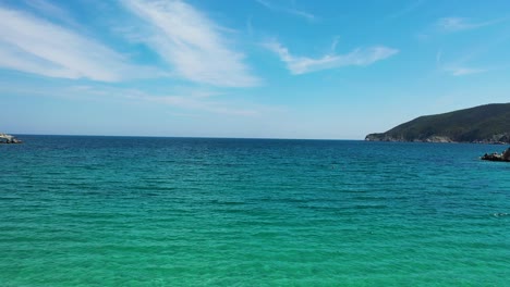 Empty-sandy-beach-with-crystal-clear-turquoise-blue-water-by-the-Mediterranean-coast-in-Greece