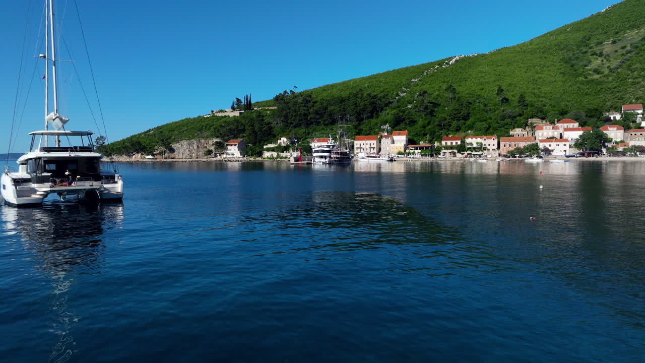 Boats Moor In The Coast With Catamaran And Trstenik Village In Summer In Peljesac Peninsula, Croatia. - aerial shot