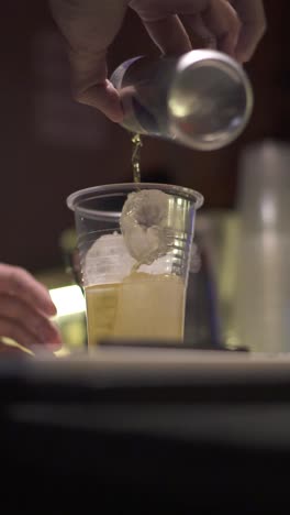 close-up of bartender preparing a cocktail with ice in a plastic glass at a party. argentina. vertical.
