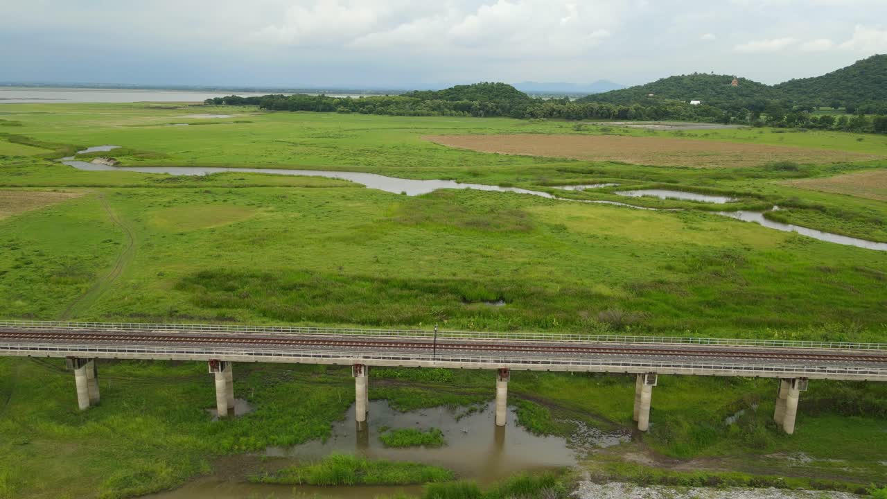 Super lovely landscape with a provincial elevated railway on a marshland, aerial sliding footage to the right, Muak Klek, Saraburi, Thailand
