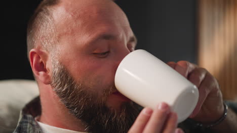 hombre barbudo toma píldora bebiendo con agua de taza blanca