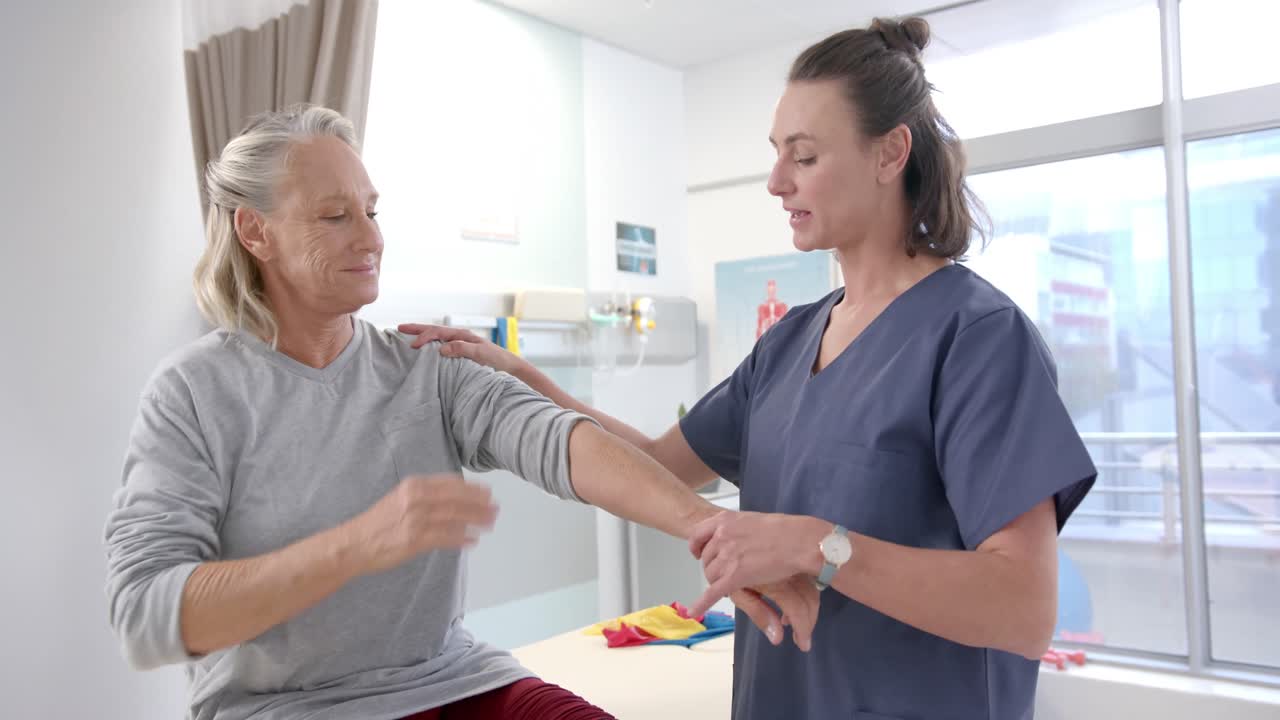 fisioterapeuta caucásica estirando la mano de una paciente mayor en el centro de rehabilitación