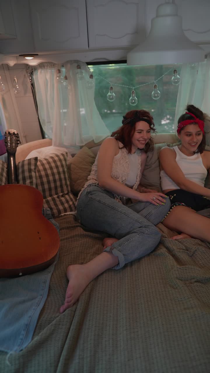 Two Women Relaxing in a Camper Van, Using a Laptop
