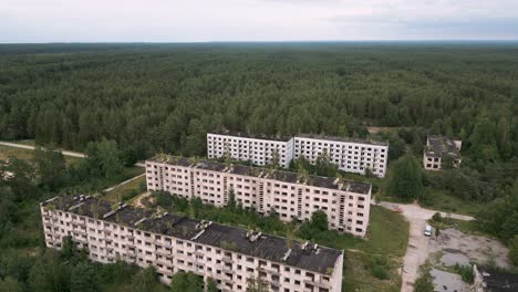 irbene, letonia - vuelo aéreo descendente con drones sobre la ciudad fantasma soviética de udssr en letonia, en medio del bosque interminable con casas soviéticas que se derrumban y con oficiales militares perdidos de los viejos tiempos