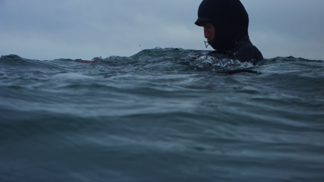 Blurred water level as photographer moves into choppy Atlantic surf with camera, slow motion