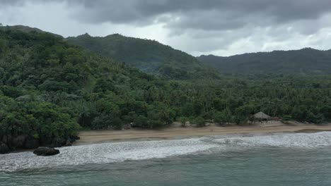 Vista-Aérea-De-La-Playa-De-Arena-Tropical-Con-Montañas-Verdes-En-El-Fondo-Durante-El-Día-Gris-Nublado---Playa-El-Valle,-República-Dominicana