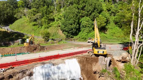 aerial view of an excavator operating at a roadwork site in uki, nsw, under bright daylight