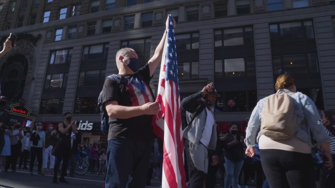 A citizen of New York City holds an American flag during spontaneous celebrations in Times Square after it is announced that Joe Biden and Kamala Harris have won the 2020 Presidential election.