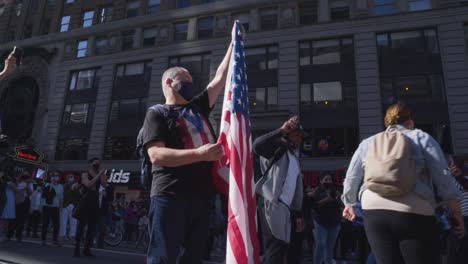 a citizen of new york city holds an american flag during spontaneous celebrations in times square after it is announced that joe biden and kamala harris have won the 2020 presidential election.