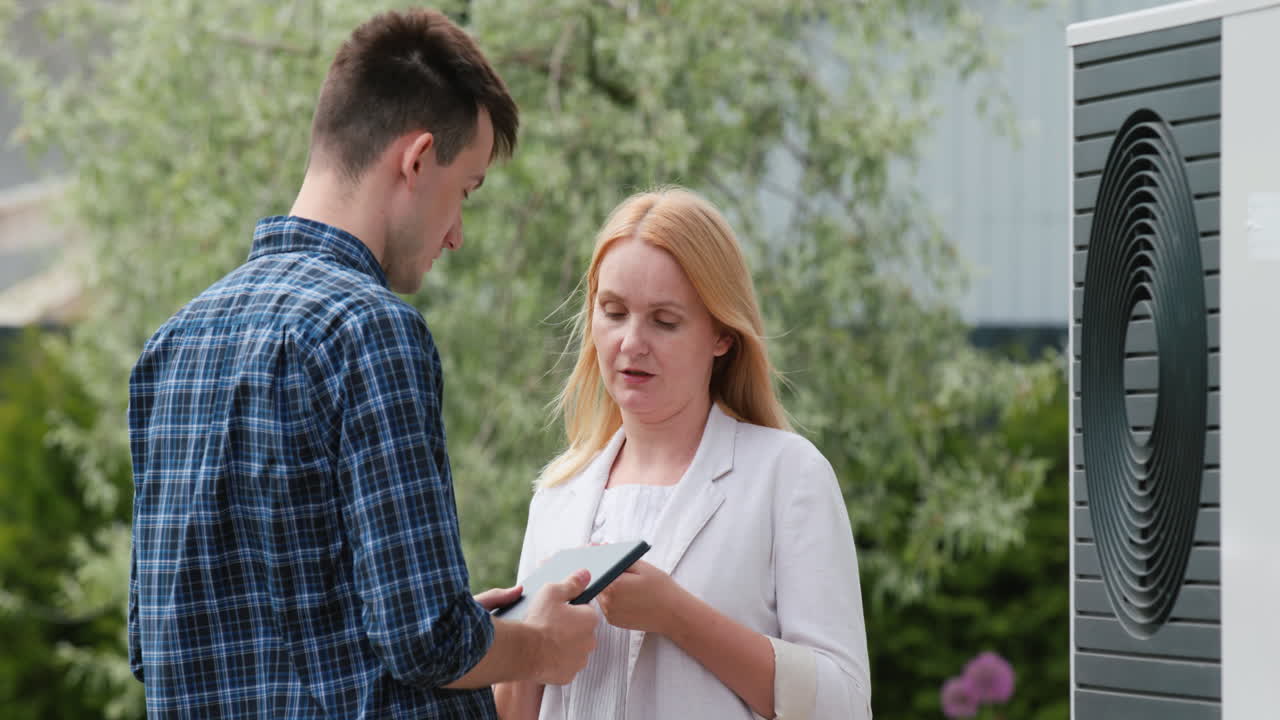 молодой инженер консультирует клиента по установке теплового насоса