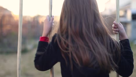 little girl playing alone on the swings of a swing set hair blowing in the breeze late afternoon sunset b roll