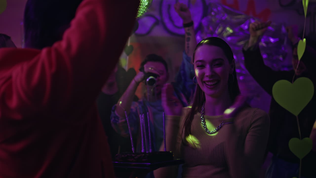 Surprised woman blowing cake candles at birthday party in nightclub closeup