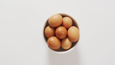 close up of bowl of brown eggs with copy space on white surface